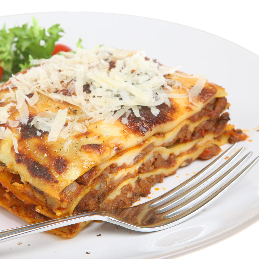 Beef lasagna with grated Parmesan cheese and salad